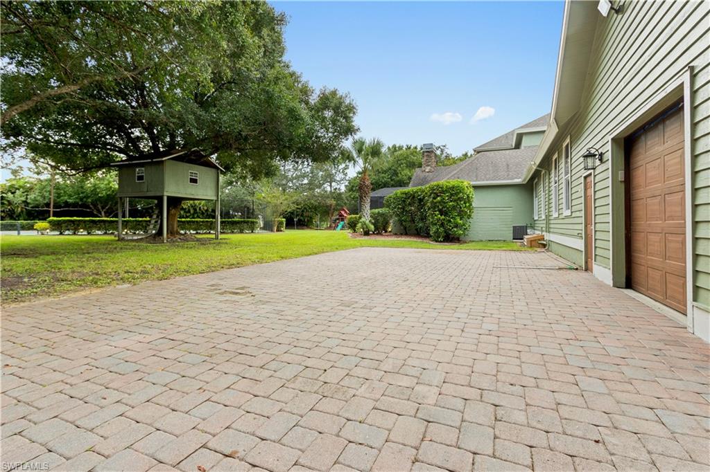 Expansive paver driveway leading to a two-car garage with wood-paneled doors