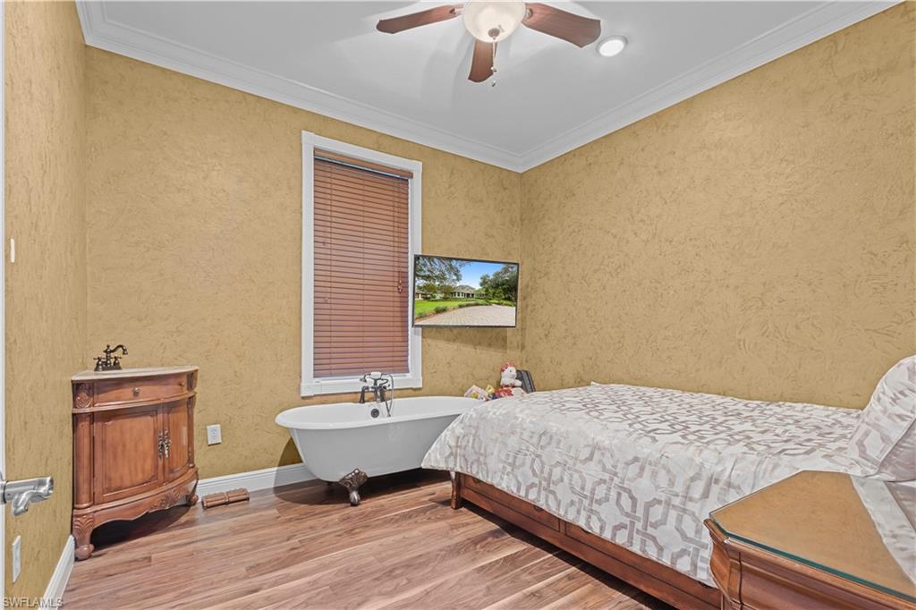 Bedroom featuring wood-finish flooring, textured wall finish, and crown molding