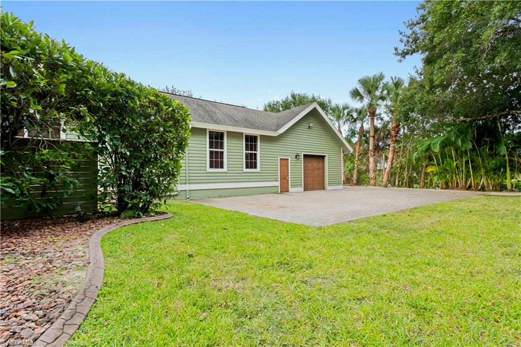Expansive green lawn with a defined landscape border and concrete driveway