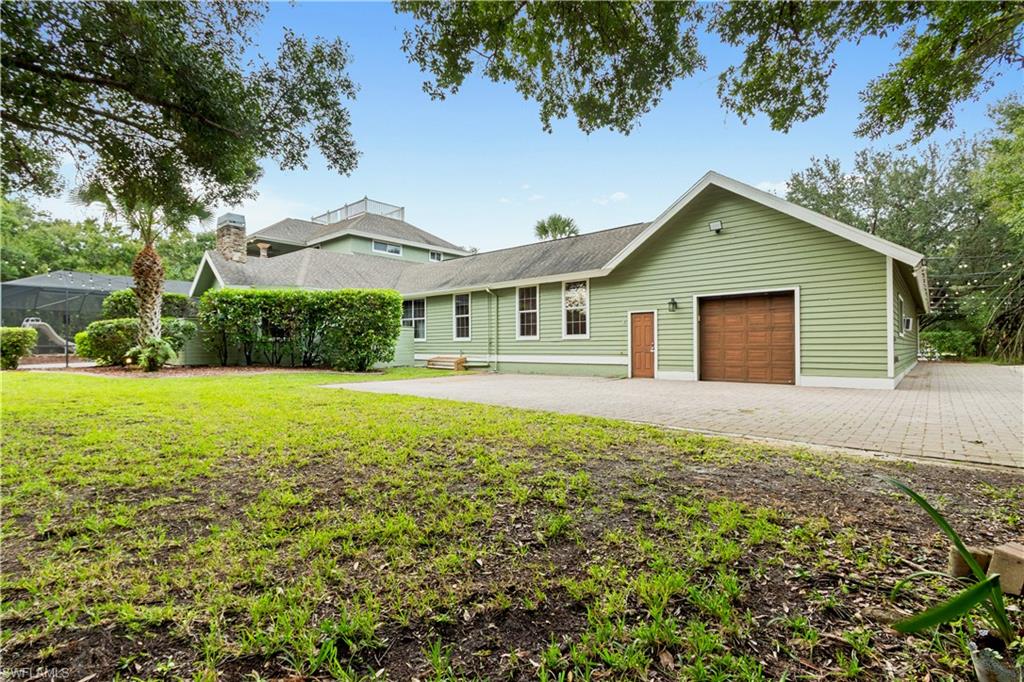 Rear exterior featuring light green siding, a brown garage door, and multiple windows