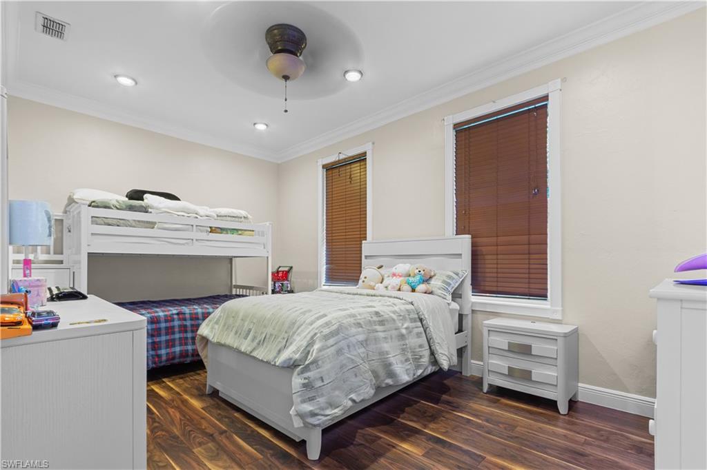 Room featuring wood-finish flooring, recessed lighting, crown molding, and two windows with blinds
