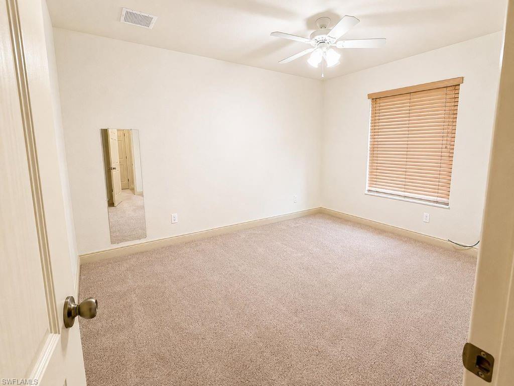 Carpeted room featuring a ceiling fan, a window with wood-finish blinds, and a mirrored wall panel