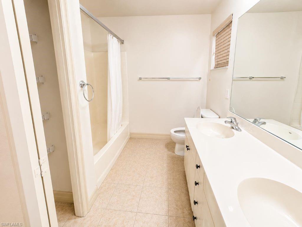 Bathroom featuring a double vanity with integrated sinks, a tub/shower combination, tiled flooring, and a large wall-mounted mirror