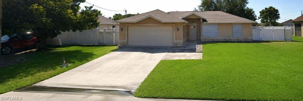 Siding exterior with a two-car garage, mature front yard tree, and an expansive concrete driveway