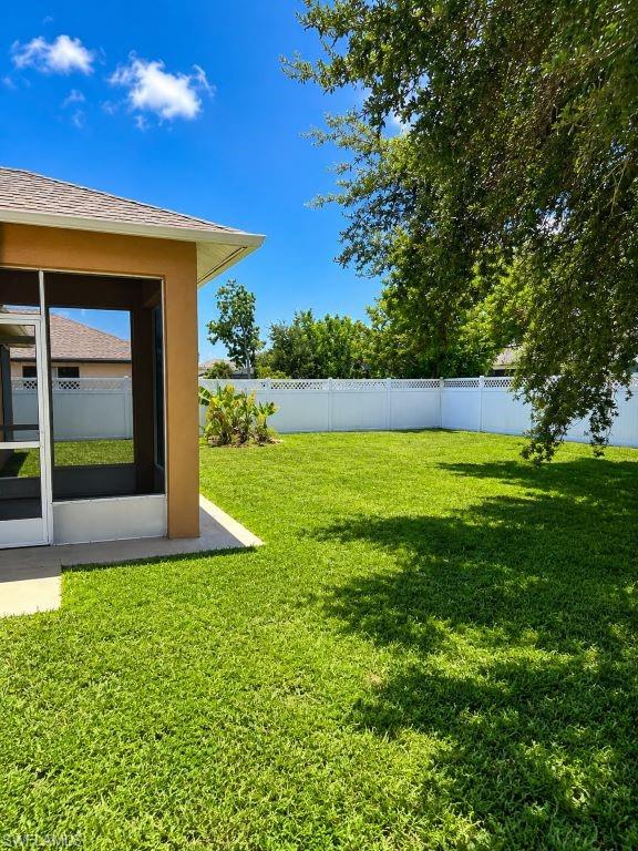 Expansive grassy lawn bordered by a white privacy fence, featuring a screened patio area and mature trees