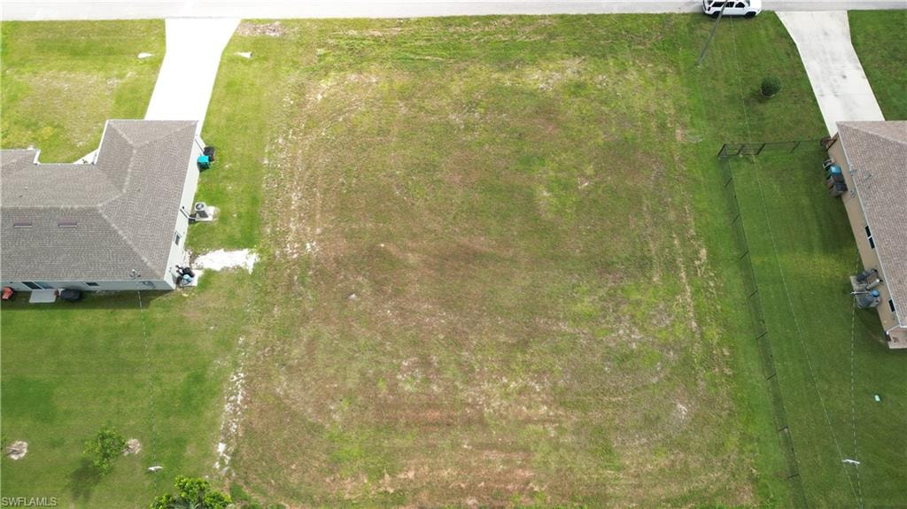 Expansive cleared lot featuring established green space, partial fencing, and direct paved road access