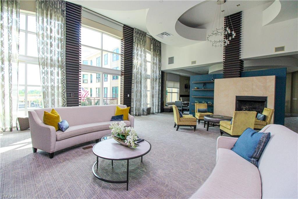 Living room with a high ceiling, carpet flooring, a tile fireplace, and a wealth of natural light