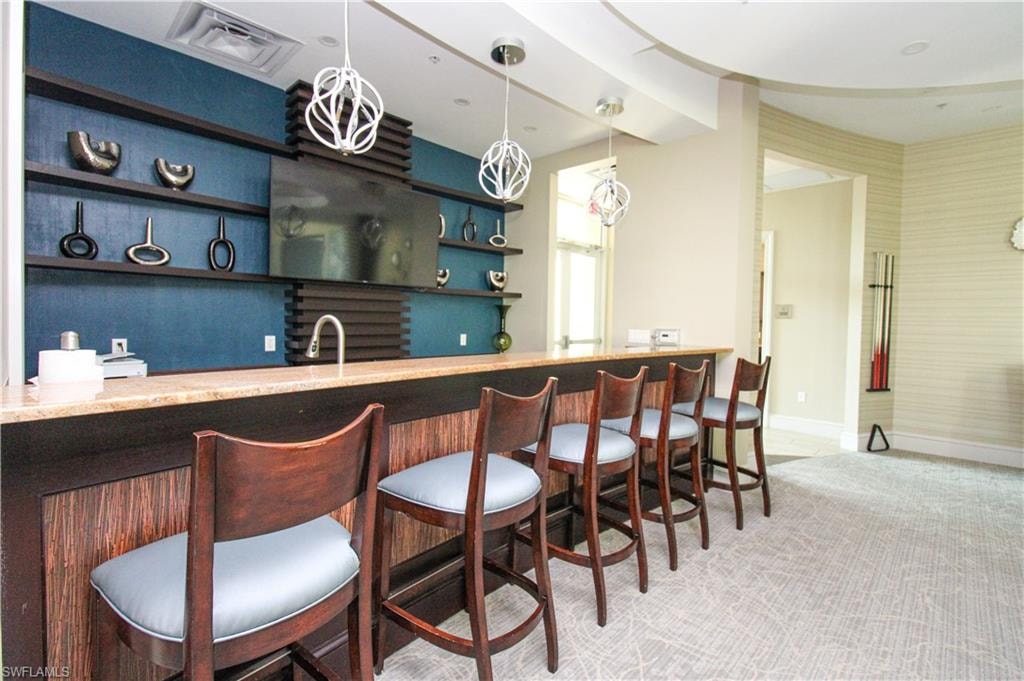 Bar featuring carpet flooring, sink, and hanging light fixtures
