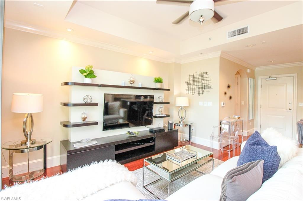 Living room featuring ceiling fan, crown molding, and wood-type flooring