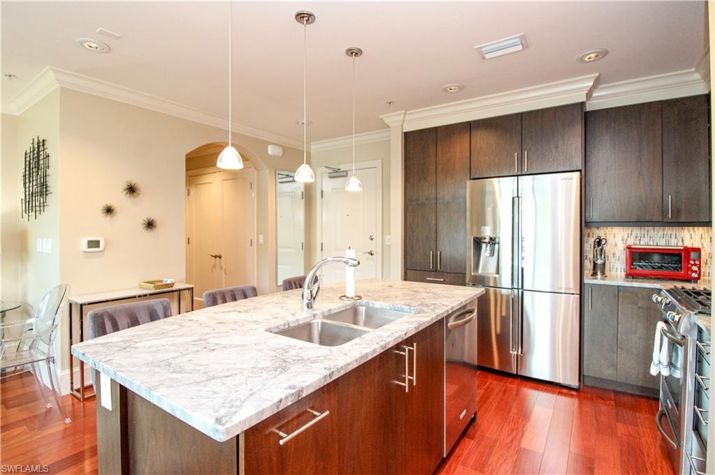 Kitchen featuring pendant lighting, dark wood-type flooring, stainless steel appliances, and sink