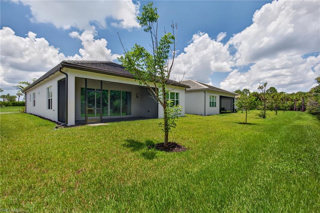 Expansive grassy yard surrounding a contemporary stucco exterior with a screened patio