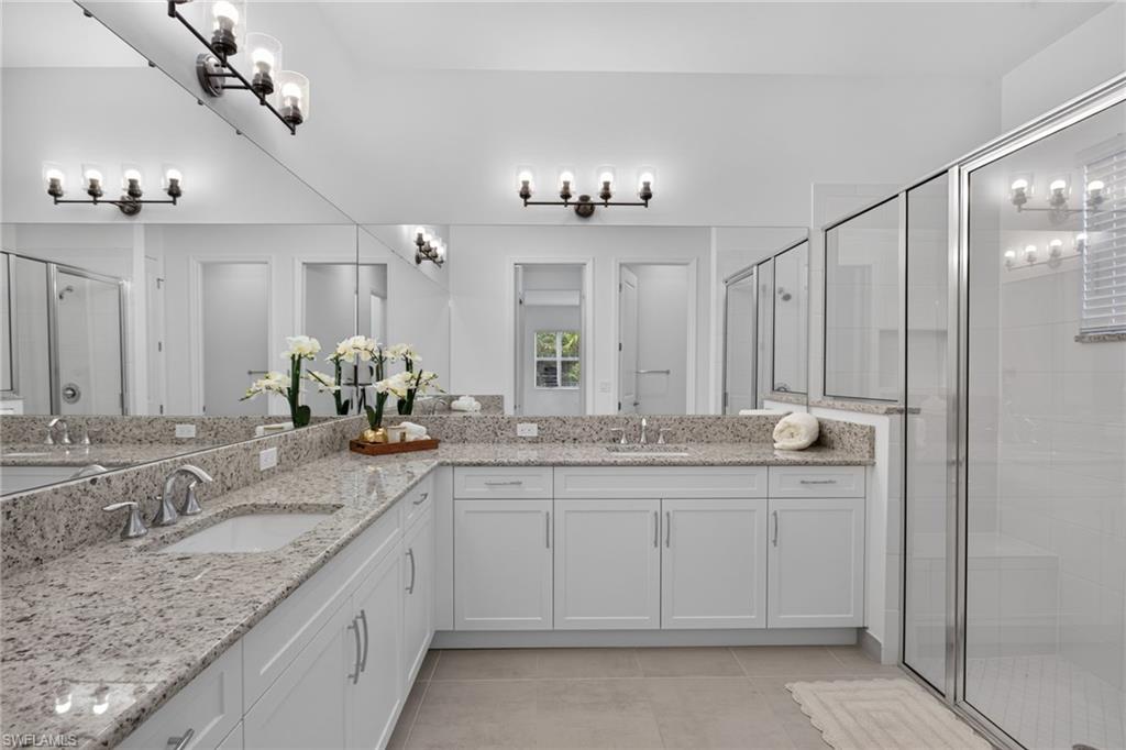 Spacious bathroom featuring a dual vanity with light-toned granite countertops and white cabinetry