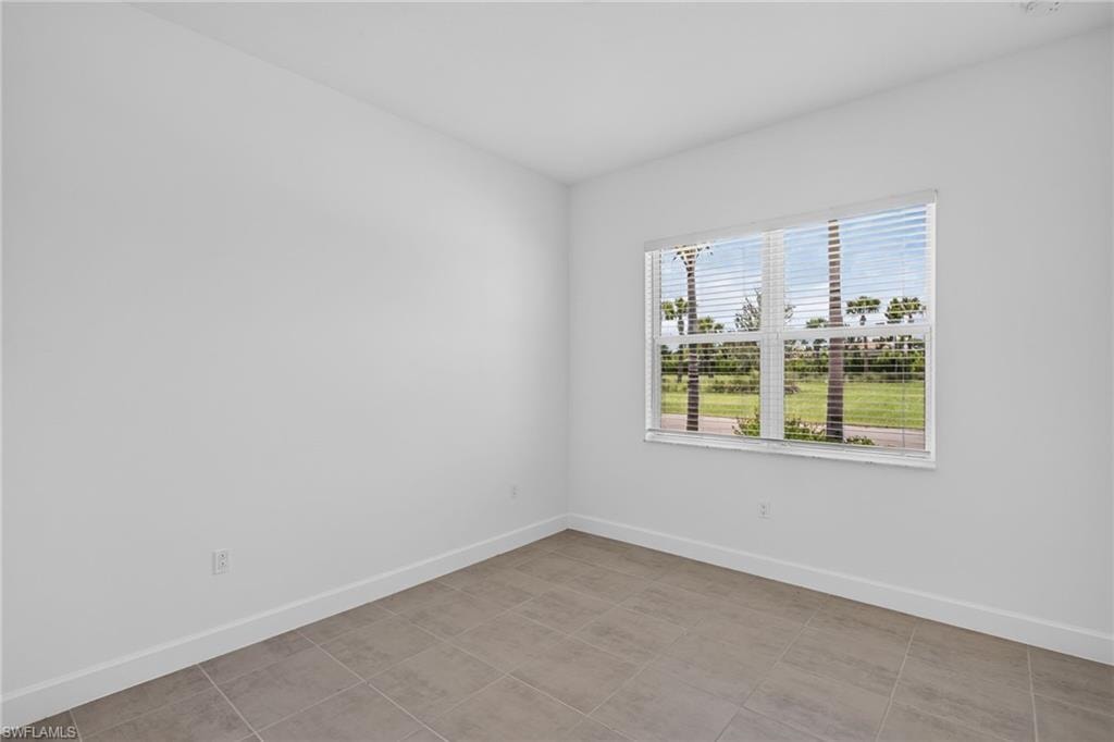 Bright room featuring a large window with horizontal blinds, neutral wall paint, white baseboards, and tile flooring