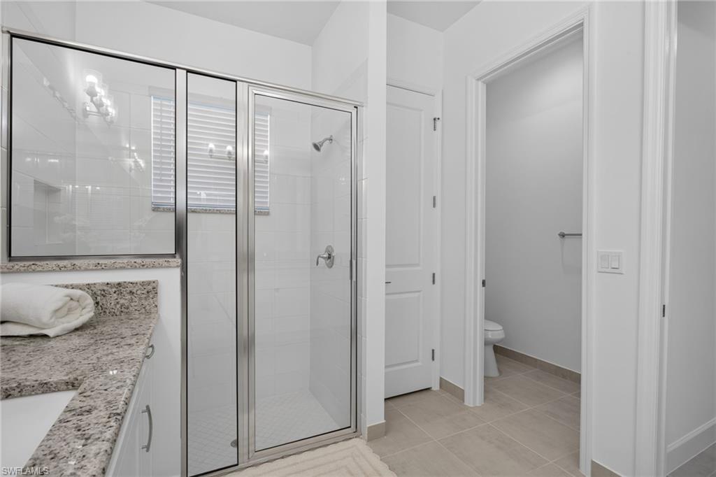 Glass-enclosed shower with chrome fixtures and white tiled walls