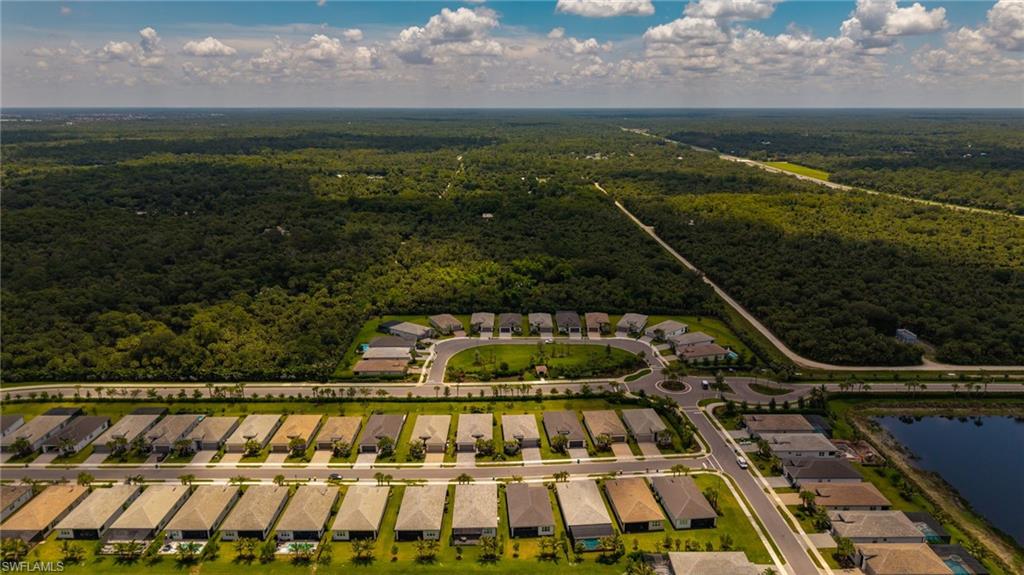 Aerial perspective of a developed residential community bordered by expansive natural green spaces