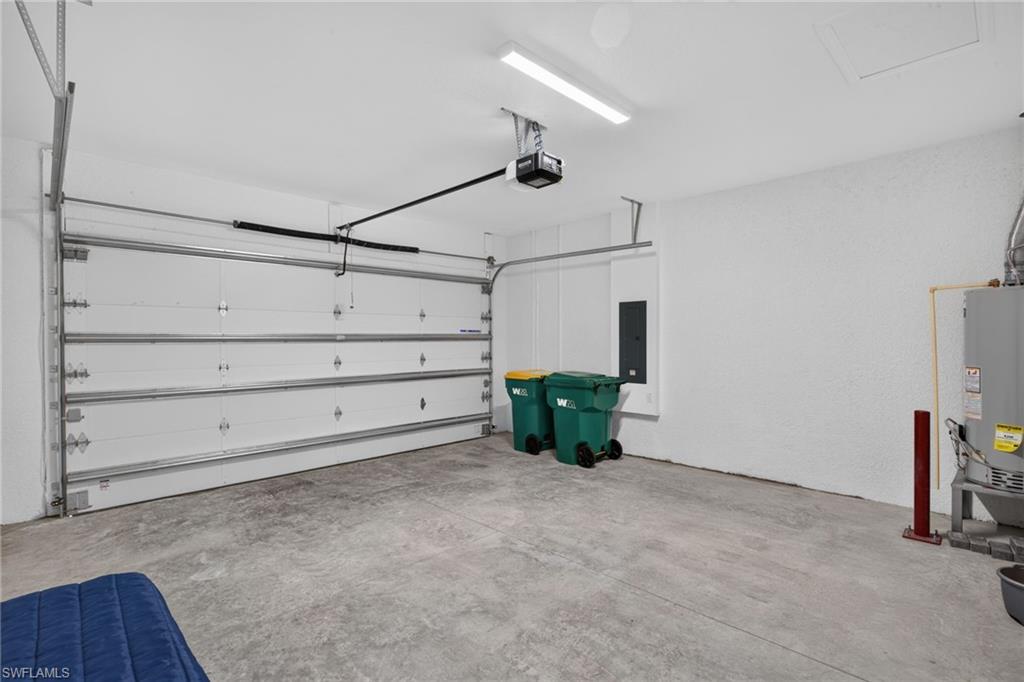 Spacious garage with a sectional overhead door, automatic opener, concrete flooring, and a water heater