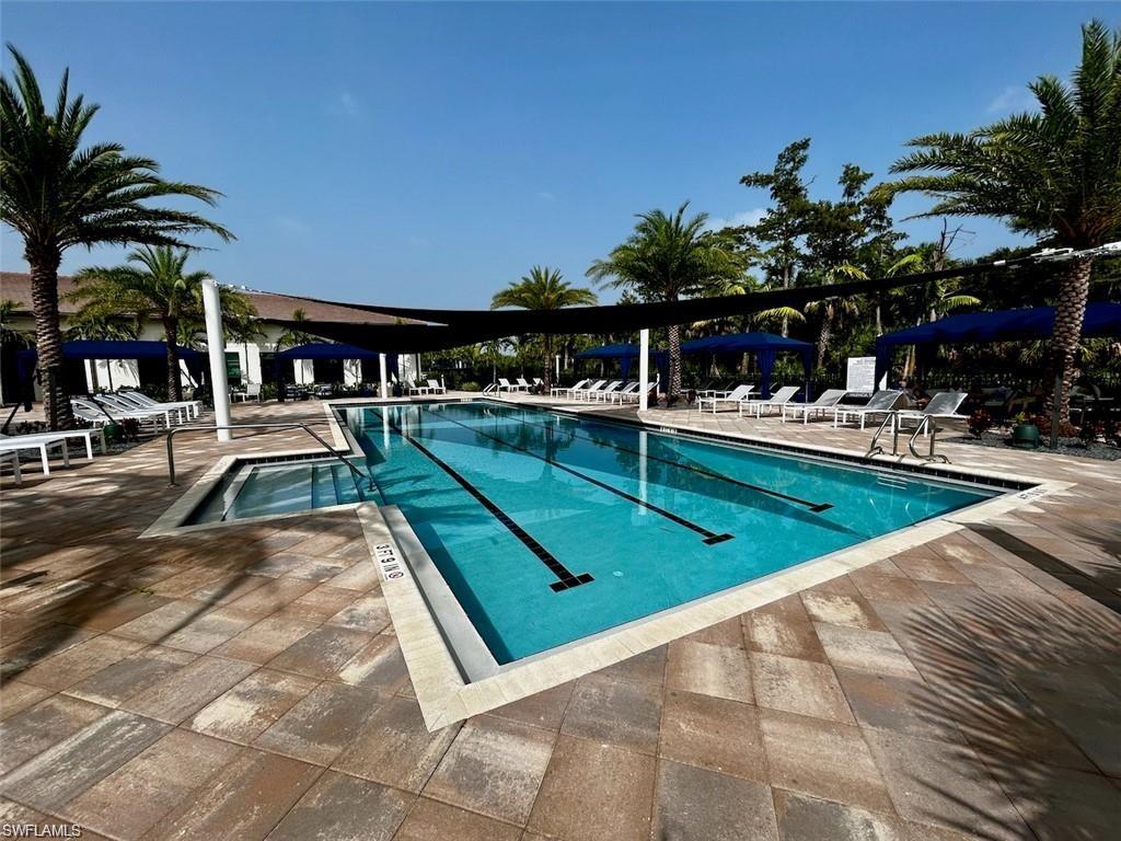 Expansive outdoor pool area featuring a rectangular swimming pool with lap lanes, an integrated spa, and surrounding paver decking