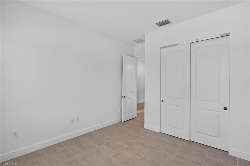 Room featuring neutral-toned tile flooring, white baseboards, and bright white walls