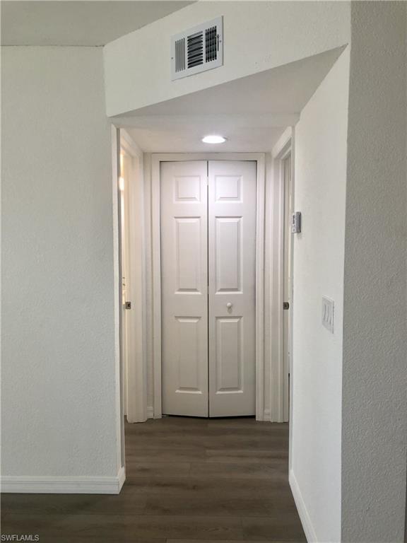 Hallway featuring wood-finish flooring, white walls, and recessed lighting