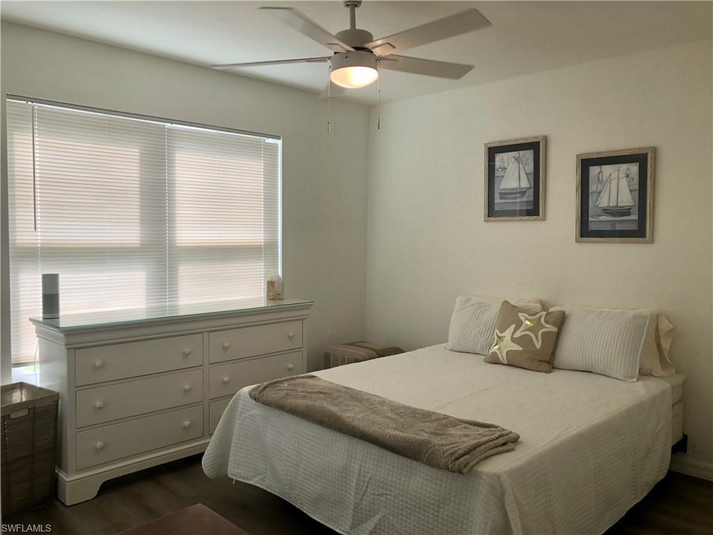 Room featuring a ceiling fan with integrated lighting, wood-finish flooring, and light-toned walls