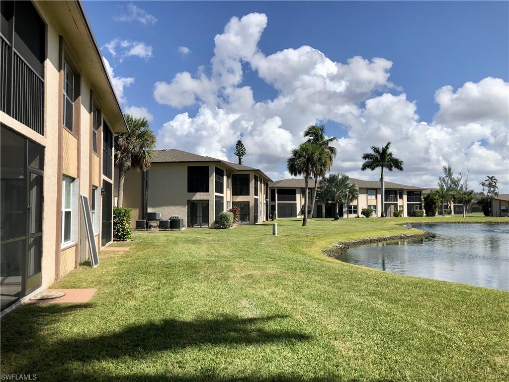 Lakeside condominium complex featuring mature palm trees and expansive green spaces