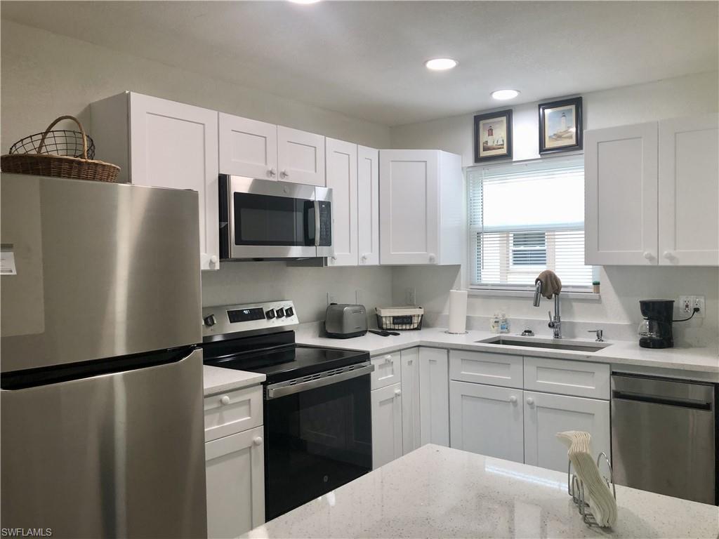 Kitchen featuring white shaker-style cabinetry, stainless steel appliances, recessed ceiling lighting, a window with horizontal blinds, and light-toned countertops