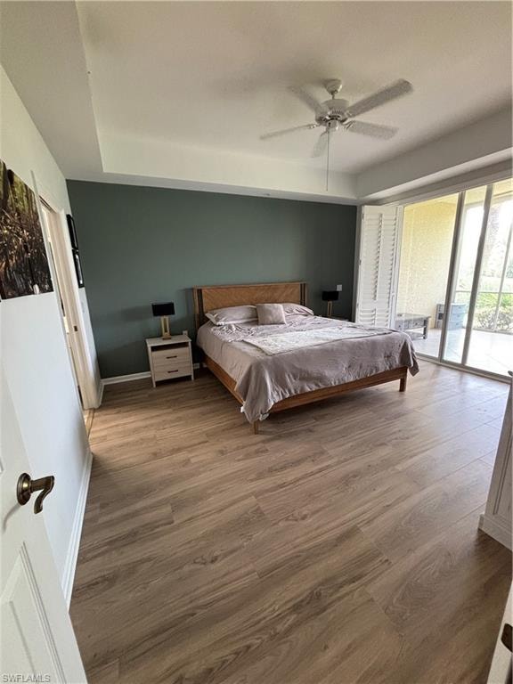 Bedroom featuring wood-finish flooring, a tray ceiling, and a ceiling fan.  New King size bed and mattress