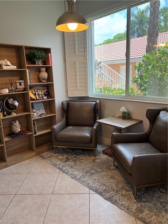 Bright interior space featuring a large window with white plantation shutters, a dome pendant light fixture, and light-toned square floor tiles