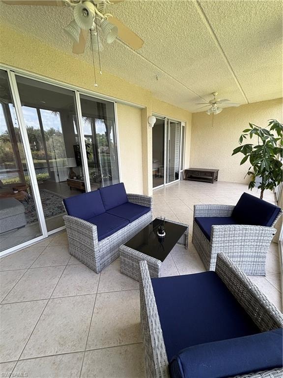 Spacious covered patio featuring large format tile flooring, multiple ceiling fans, and sliding glass doors