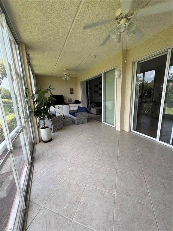 Expansive screened lanai featuring ceramic tile flooring, multiple ceiling fans, and direct access to interior spaces through large sliding glass doors