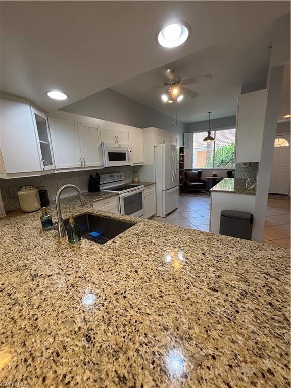 Kitchen featuring speckled granite countertops, white cabinetry, undermount sink with gooseneck faucet, and recessed lighting