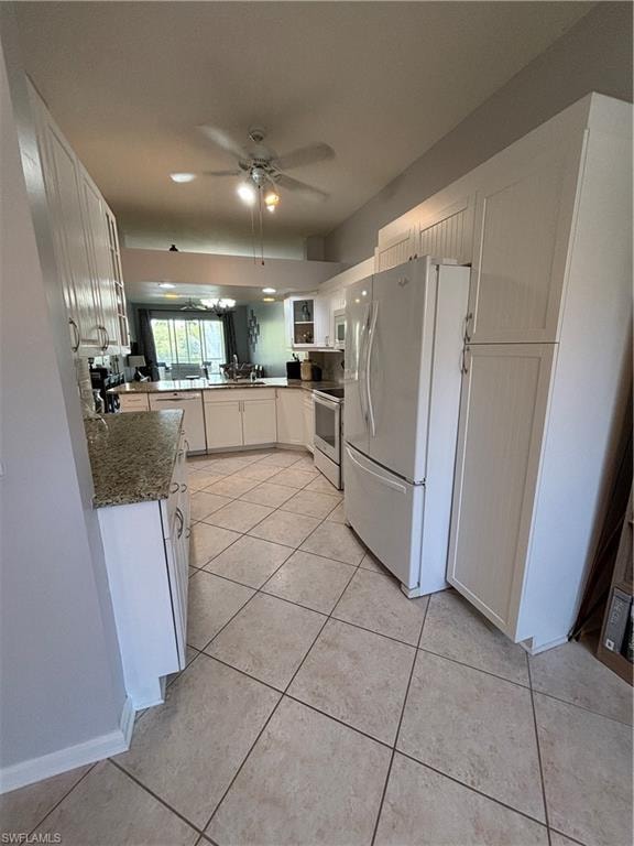 Kitchen featuring tile flooring, white cabinetry, integrated appliances, recessed lighting, and granite-finish countertops