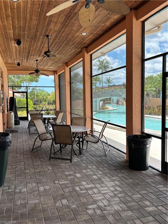 Clubhouse lanaii with a ceiling fan, brick floors, wooden ceiling, and outdoor dining space