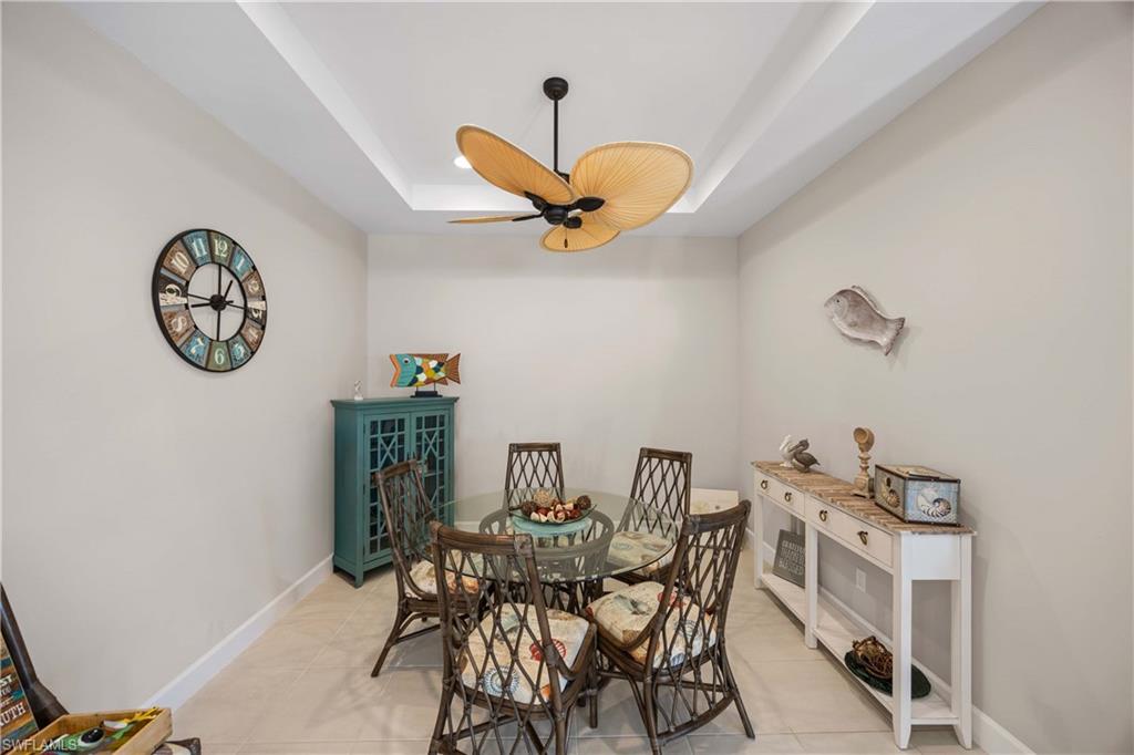 Dining space with a raised ceiling, light tile patterned floors, and ceiling fan