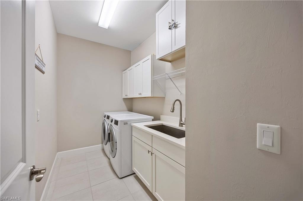 Laundry room featuring cabinet space, light tile patterned flooring, and separate washer and dryer
