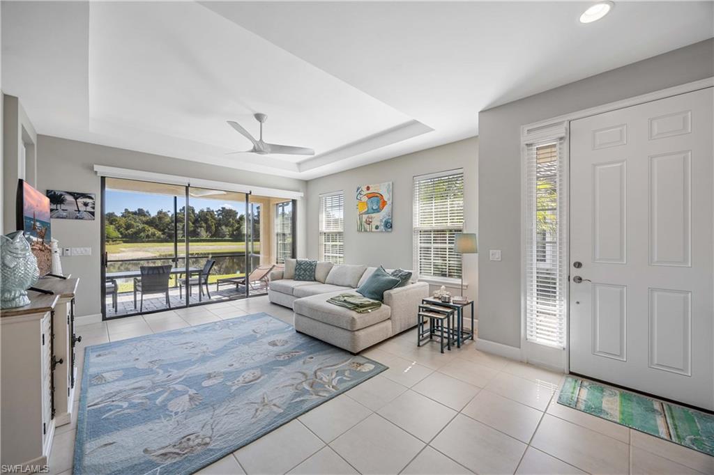 Living area with light tile patterned floors, a raised ceiling, plenty of natural light, and ceiling fan
