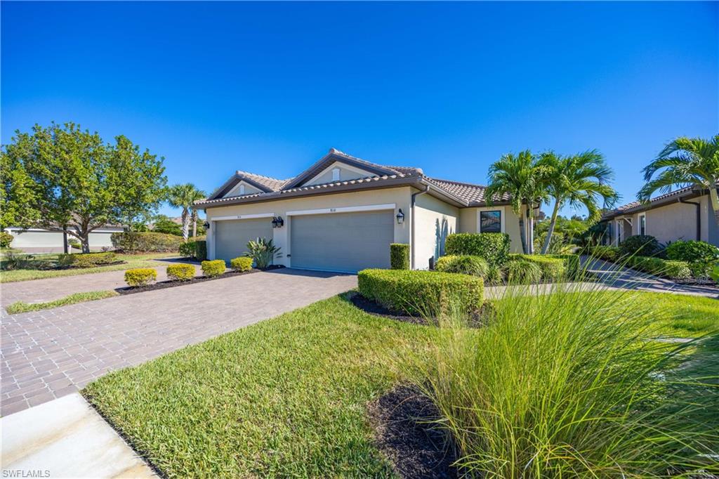 View of front of house featuring a tiled roof, stucco siding, a front yard, decorative driveway, and an attached garage