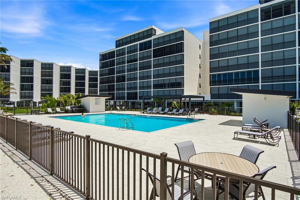 Expansive outdoor pool area featuring a rectangular swimming pool, surrounding paver decking, and a perimeter safety fence
