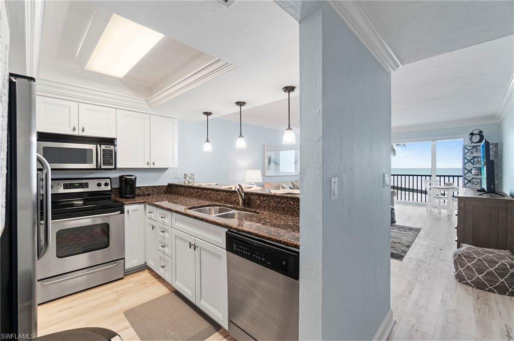 Modern kitchen featuring stainless steel appliances, white cabinetry, a double basin sink, and a breakfast bar