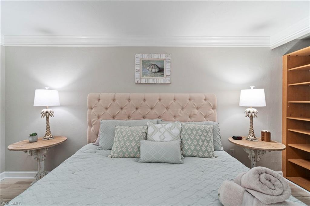 Bedroom featuring a tufted upholstered headboard, crown molding, and built-in shelving