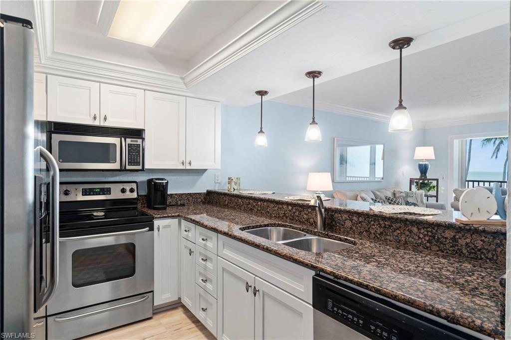 Kitchen featuring stainless steel appliances, white cabinetry, dark granite countertops, and a double basin sink