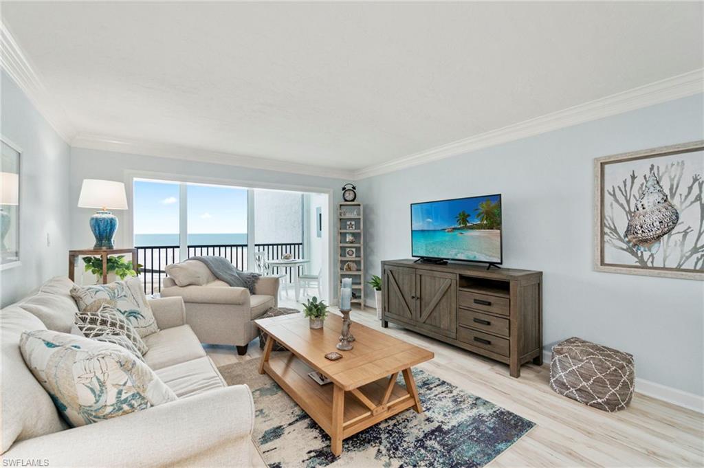 Living room with expansive glass sliding doors opening to a balcony with ocean views