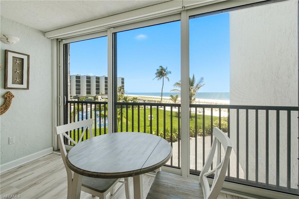 Expansive sliding glass doors open to a balcony featuring black railings, offering a direct ocean vista