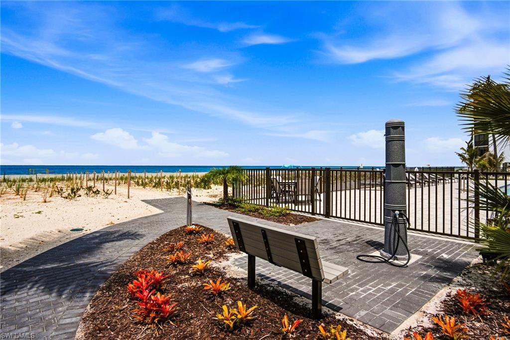 Beachfront access featuring a paver pathway, decorative landscaping, and a convenient outdoor shower