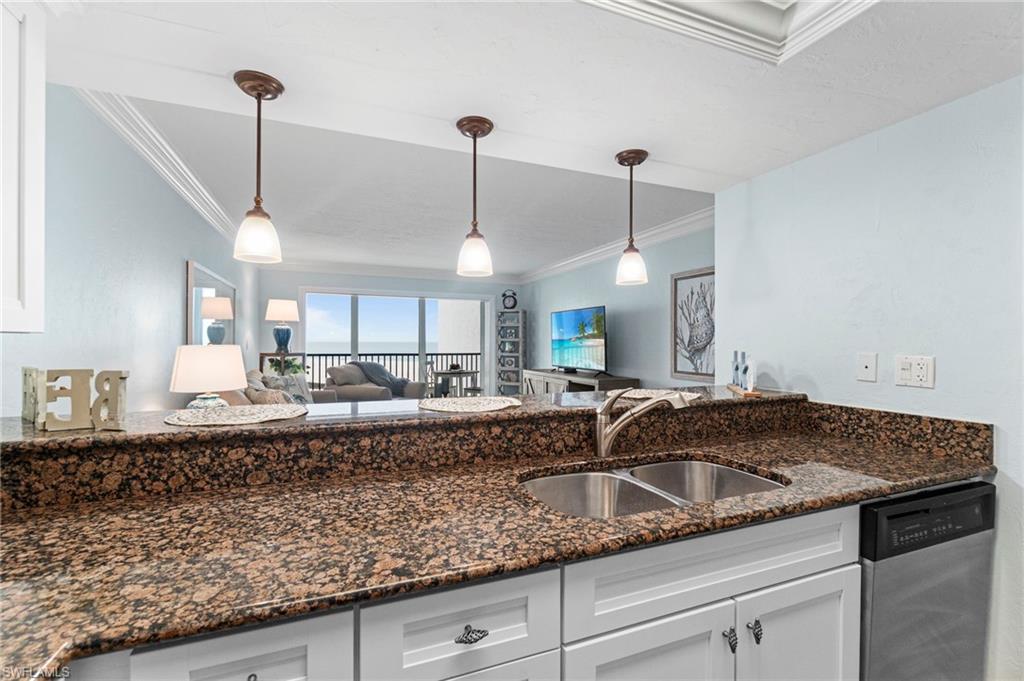 Kitchen featuring a double basin stainless steel sink with a high arc faucet, granite countertops, and white cabinetry
