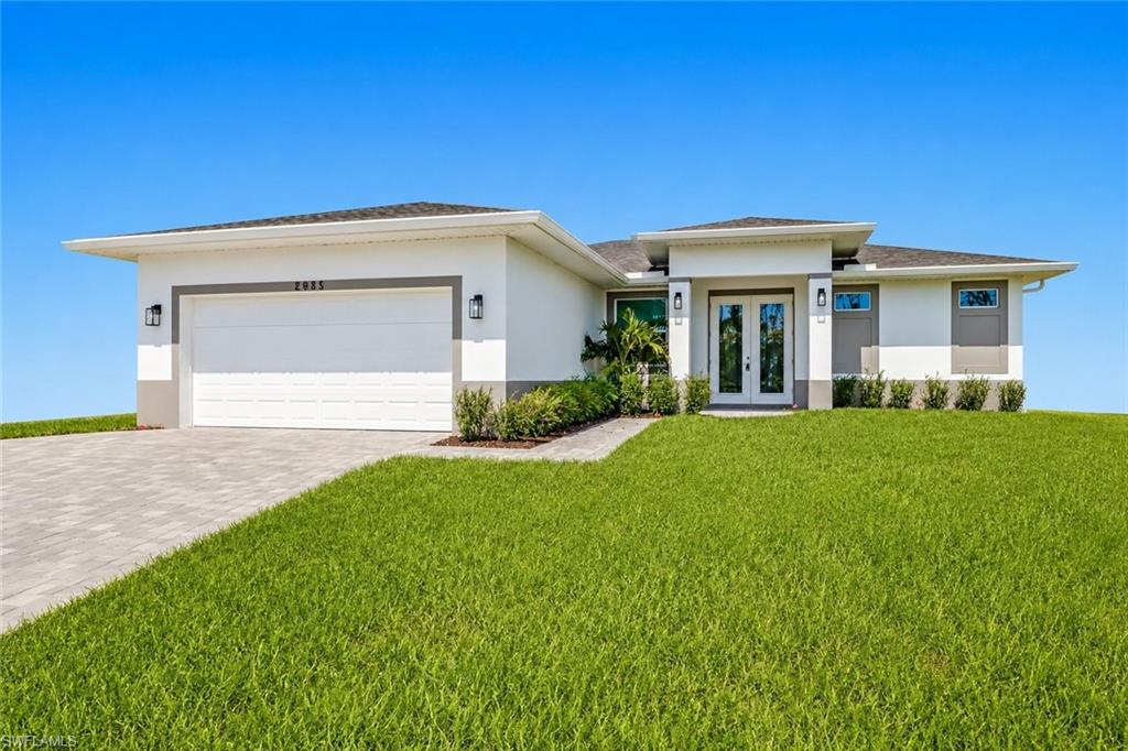 Contemporary exterior featuring a white facade with gray accents, a paved driveway, an attached garage, a double-door entry with sidelights, and established landscaping