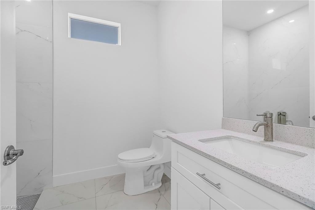 Bathroom featuring a white vanity with a speckled countertop, undermount sink, and brushed nickel faucet
