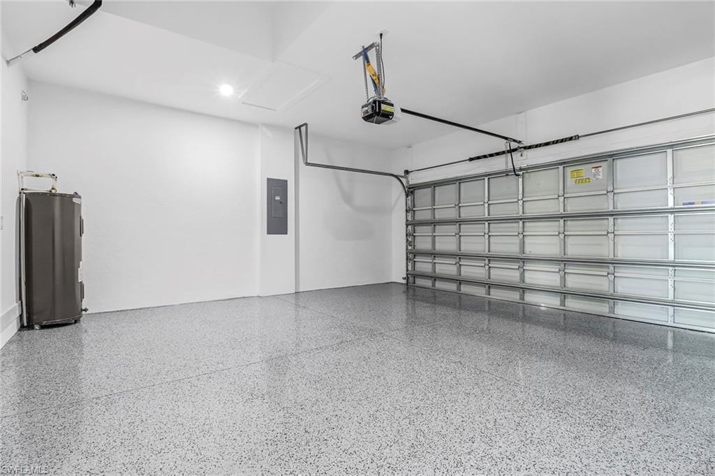 Spacious garage featuring a durable epoxy-coated floor, automatic overhead door, recessed lighting, and a utility panel