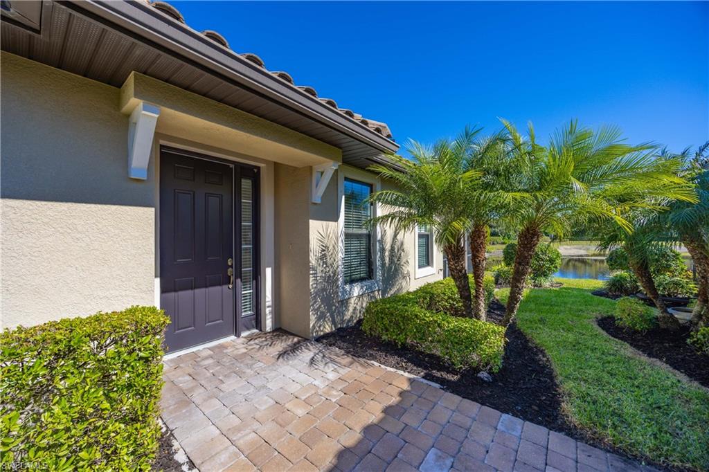 Entrance to property with stucco siding, a lawn, and a water view