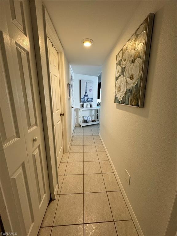 Hallway featuring baseboards and light tile patterned flooring